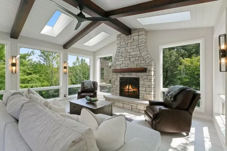 Modern sunroom with skylight, fireplace, comfortable seating, and expansive windows overlooking green landscape
