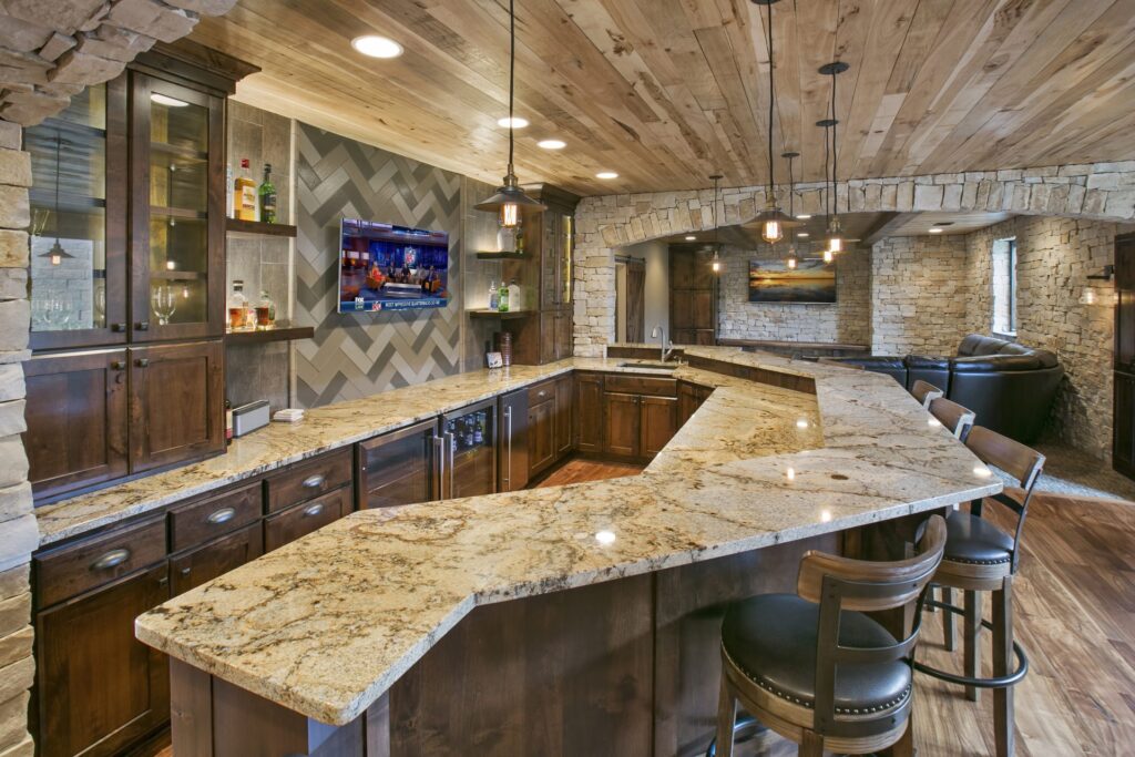 spacious basement U-shaped bar with granite countertops, dark wood cabinetry, built-in appliances, and wraparound seating area